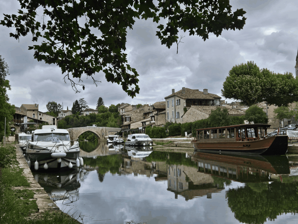 Le SHIMA amarré au port d'un village, sous un pont de pierre en arche, une gabare de bois sur la rive d'en face